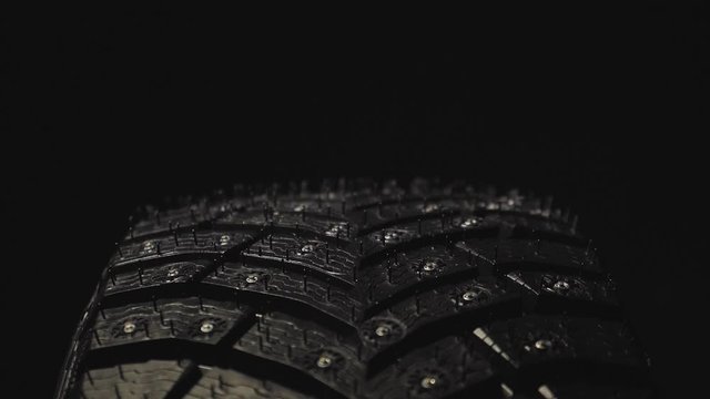 Car Winter Tire with Studded on Black Background