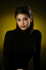 Studio portrait of a beautiful young brunette in a black shirt on a dark background, neutral facial expression