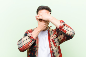 young handsome man covering face with both hands saying no to the camera! refusing pictures or...