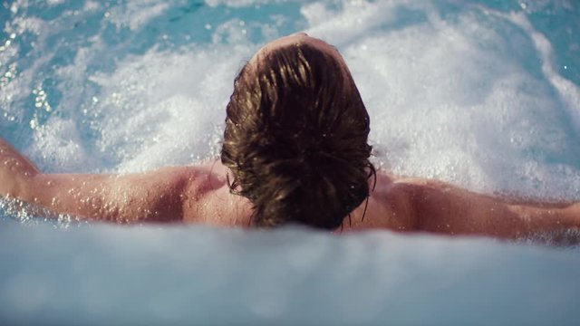 brunette woman under the splash shower on a hot, sunny summer evening in a luxurious pool - br&uuml;nette Frau unter der Schwalldusche  an einem hei&szlig;en, sonnigen Sommerabend in einem luxuri&ouml;sen Pool.