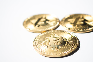 The close up of three gold Bitcoins in plain background.