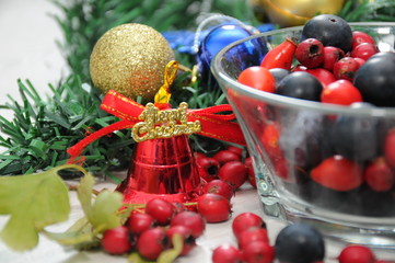 Forest fruit with Christmas decorations bells and balls next to the Christmas tree