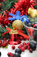 Forest fruit with Christmas decorations bells and balls next to the Christmas tree