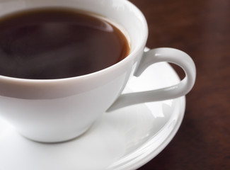 A cup of hot americano coffee or hot espresso coffee on wooden table. Close up and selective focus.