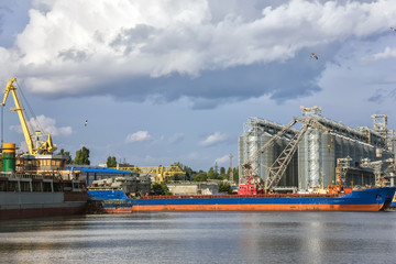 Fototapeta na wymiar ships for grain transportation and port cranes for loading.River port terminal. Transportation of agricultural products. Soft focus