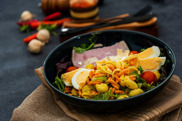 Salad made with cooked pasta, mixed green salads, cherry tomatoes, Mozzarella cheese and smoked ham served with accompaniment