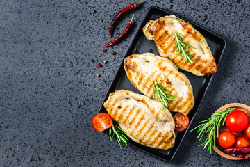 Stuffed chicken breasts, cast iron sheet pan on dark background. Top view.