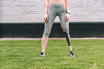 partial view of disabled sportswoman with fitness tracker on grass