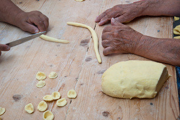 Knead the homemade orecchiette baresi. Typical fresh pasta from Bari, Puglia region, Italy. Working hands. Hands of an old woman. Italian small business owners. Ancient tradition.
