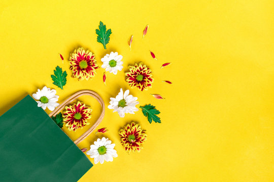 Flowers composition yellow and white asters spilled out green paper bag  Rustic style. St. Valentine's Day, Women's day, Happy birthday concept place for your text. Flat lay, top view photo mock up