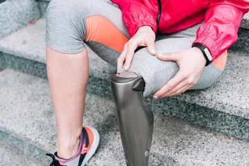 partial view of disabled sportswoman with prosthesis sitting on stairs
