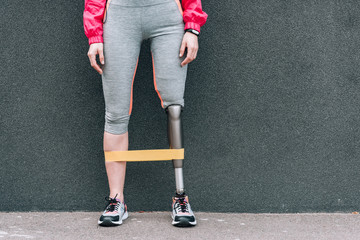 partial view of disabled sportswoman with resistance band on street