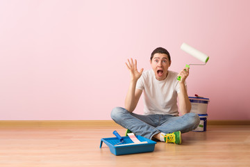 Man with paint roller sitting on the floor