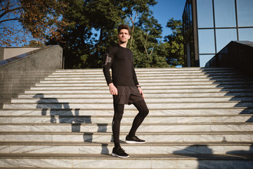 Young handsome confident sporty man thoughtfully looking away on morning run in park