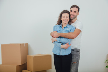 Fototapeta na wymiar Couple moving into their new house, husband is hugging his wife,looking at the camera, smiling.