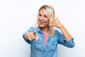 Obraz premium Young blonde woman over isolated white background making phone gesture and pointing front