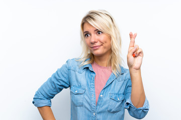 Young blonde woman over isolated white background with fingers crossing and wishing the best