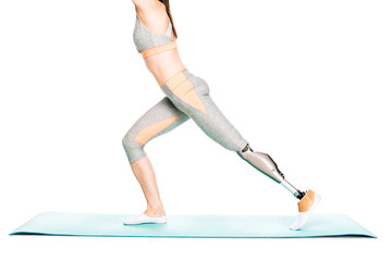 partial view of disabled sportswoman with prosthesis stretching isolated on white