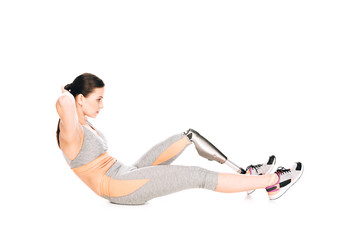 side view of disabled sportswoman with prosthesis doing sit ups isolated on white