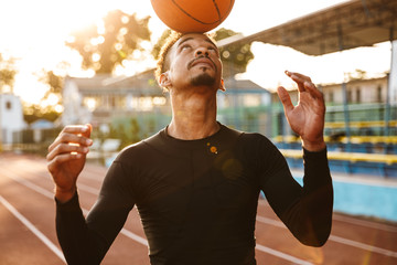 Young sports man at stadium outdoors play basketball.