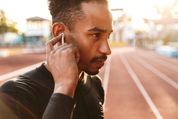 Serious handsome young sports man listening music
