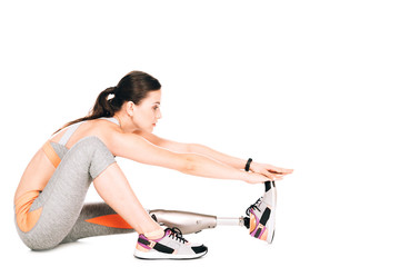 side view of disabled sportswoman with prosthesis stretching isolated on white