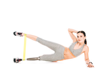 disabled sportswoman with prosthetic leg training with resistance band on white