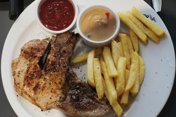 Lunch with pork chop and french fry on a white plate
