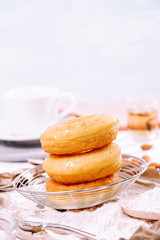 Homemade fried donuts or cronuts in stack with sugar standing on crumpled paper over white wooden concrete table.