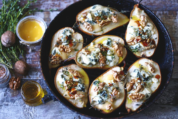 Halved Pears in a pan baked with Dorblu cheese, honey, walnuts and thyme. French cuisine. Keto diet. Selective focus.