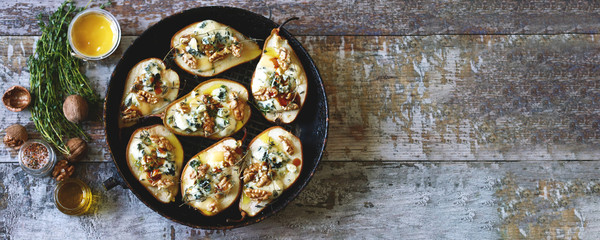 Obraz na płótnie Canvas Halved Pears in a pan baked with Dorblu cheese, honey, walnuts and thyme. French cuisine. Keto diet. Selective focus.