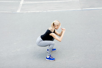 Burn in buttocks. Side view of young woman in sportswear doing squat . Young beautiful woman squats