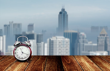 Fototapeta na wymiar Alarm clock on wooden deck with ciytscape blurred background