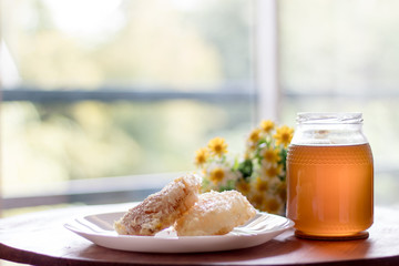 Fresh honey jar with flowers and honeycomb, delicious biological product.