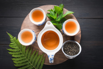 Tea ceremony. Three cup of tea with mint and kettle on dark . Chinese tea concept. View from above.