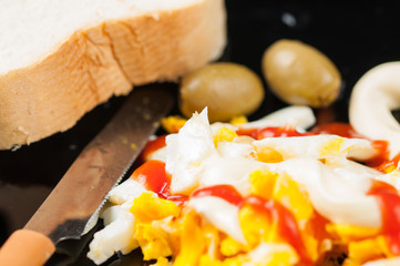 Fried egg on black plate isolated on white background.Eggs with kutchup,olives and bread