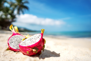 tropical fruit dragonfruit lies on a river near the sea on a background of palm trees