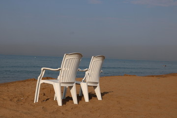 Zwei Stühle am menschenleeren Strand mit Blick auf das Meer