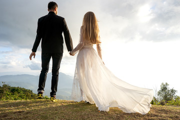 couple in love in the mountains in wedding dresses at sunset