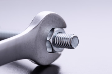 The bolt is unscrewed with a wrench. Wrench and bolt with nut close up. 