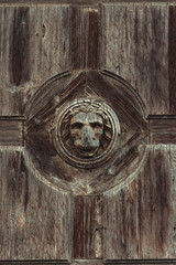 Old and weathered wooden lion head on and old wooden door