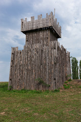 Wooden historic fort on a green meadow with blue sky with white 