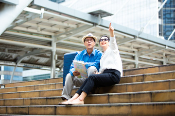 Senior couple traveling with luggage checking city map and sightseeing Travel and tourism concept.