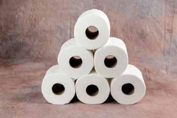 rolls oF soft toilet paper on a dusty pink cloth background