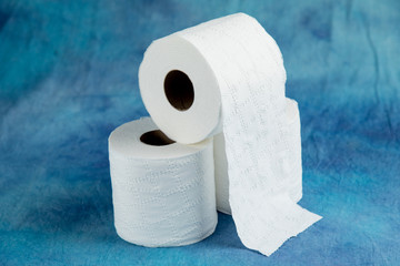 rolls of soft toilet paper on a luxurious aqua marine blue cloth background