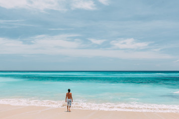 Man walking in blue lagoon with paradise view