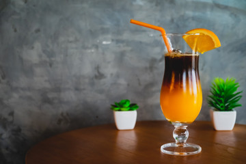 Orange juice with espresso shot on wooden table