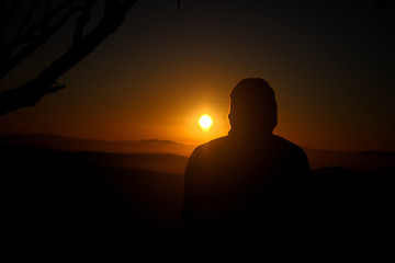 Fototapeta premium Man sitting down looking out into the sunrise