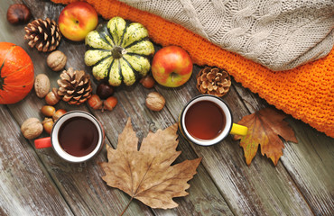 Autumn flat lay background. Pumpkins, apples, nuts,leaves, cups and sweater on wooden background.