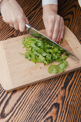 Woman hand cutting spinach using a sharped big kitchen knife